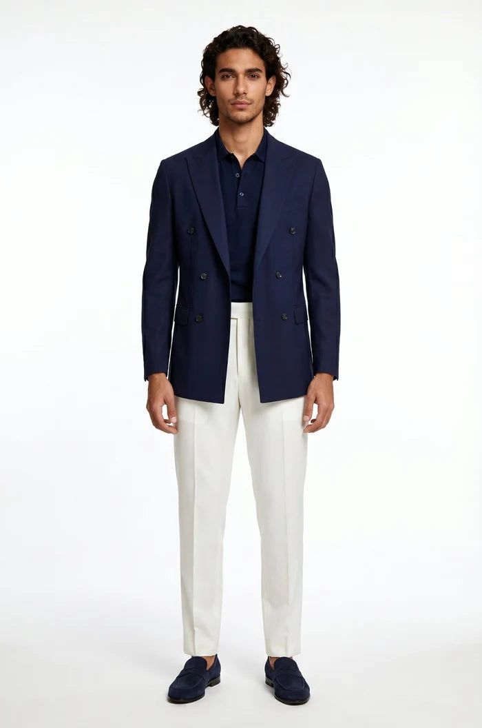 Man wearing a navy blazer, white pants, and dark shoes on a white background