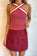 Red and white striped top with a maroon skirt against a light brick wall.