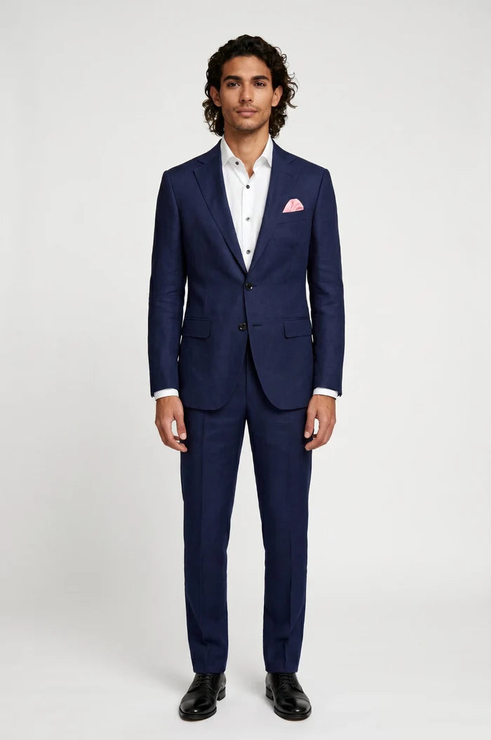 Man wearing a blue linen suit with a white shirt and pink handkerchief on a white background