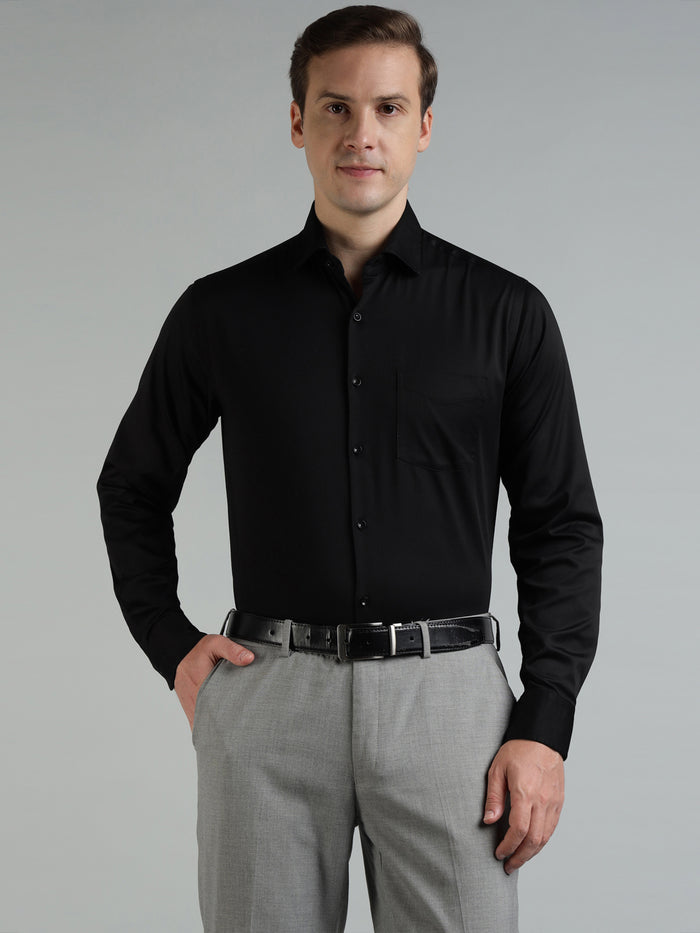 Man wearing a black dress shirt and gray pants against a gray background