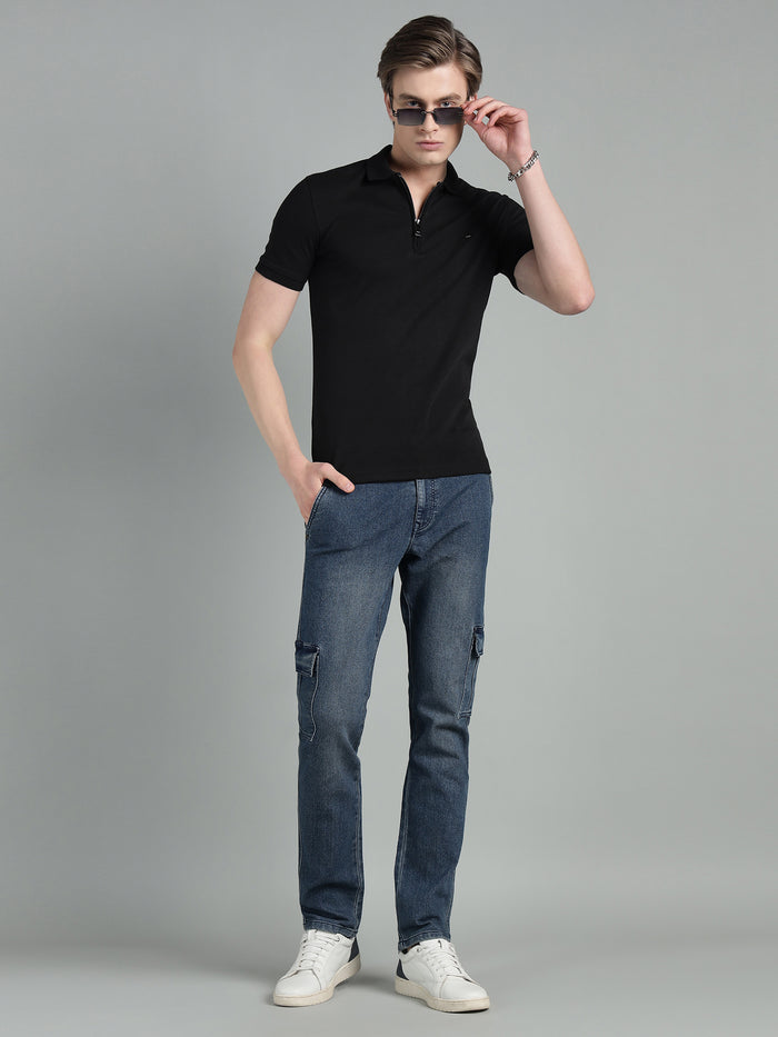 Man wearing a black polo shirt and blue jeans on a gray background