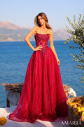 A woman wears a strapless wine-colored ball gown with sparkly embellishments against a seaside backdrop with lemons.