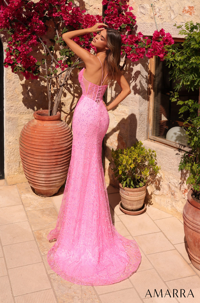 A person in a long pink sparkly mermaid dress poses elegantly beside red bougainvillea flowers and terracotta pots.