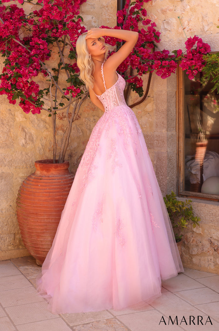 A blonde woman in a pink corseted ball gown poses beside blooming bougainvillea and a terracotta pot.