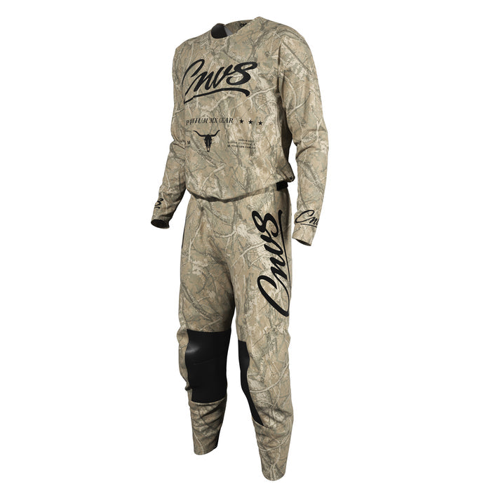 A two-piece motocross riding suit in a Realtree camouflage pattern, featuring a long-sleeve jersey and matching pants. The jersey has 'Cnvs' printed in black script across the chest, with 'REALTREE CAMO' and a bull skull logo underneath.